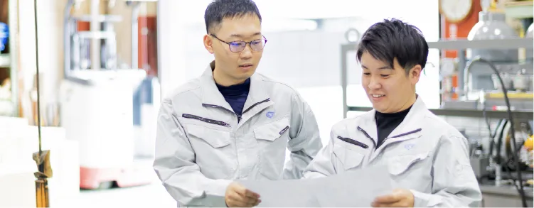 図面を確認しながら打ち合わせをする2人の社員